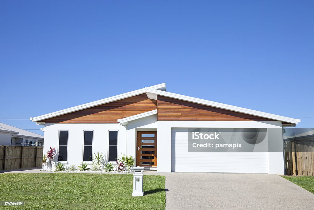 Modern Family Home Front with clear blue sky copyspace Front view of a new neat modern white low set single story family home with green grass and blue sky for copy space. House Stock Photo