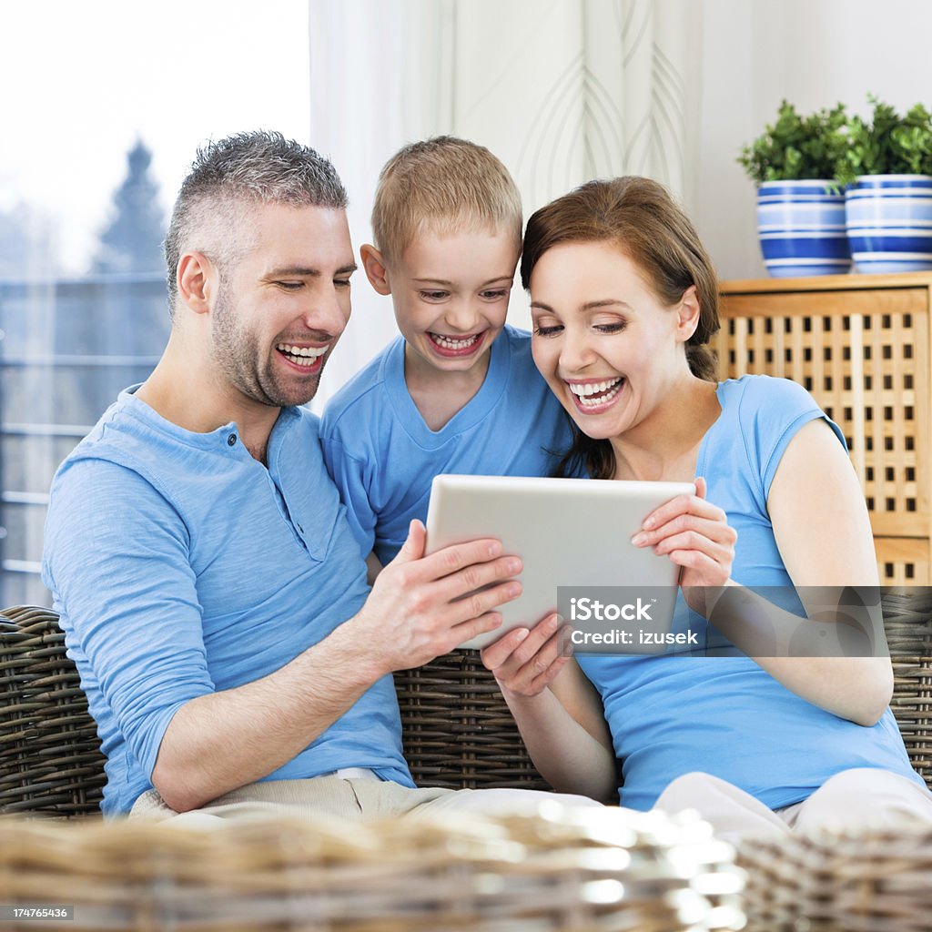 Happy Family with digital tablet Close up of a happy family sitting comfortably on couch at home and using digital tablet. 25-29 Years Stock Photo