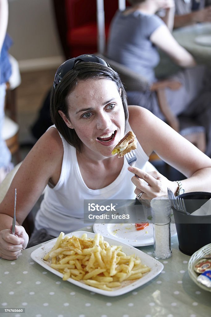 Mujer caucásica dificultades para comer un plato de papas fritas - Foto de stock de Adulto libre de derechos