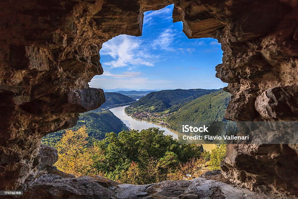 Danube River, Austria Danube River seen from a window of an ancient stone wall in the Wachau, a region in the Lower Austria along the river well-known for its wine growing area. Its beautiful landscape includes vineyards, many of which are built on terraces overlooking the Danube, villages, abbeys, and small towns rich in history, footpaths and cycle paths for discover the nature. It is about 40 kilometers (25 mi) in length and is located midway between the towns of Melk and Krems. It is inscribed in the UNESCO List of World Heritage Sites since December 2000. Danube River Stock Photo