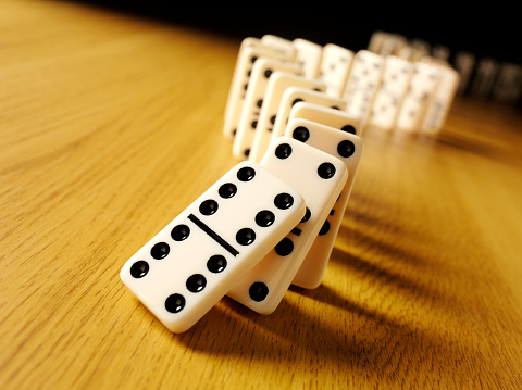 Dominoes with the domino effect on a wooden background with copy space.Click on the link below to see more of my business and leisure game images.
