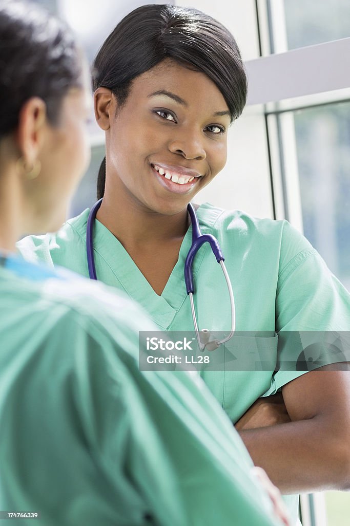 Nurses Two health care workers talking to each other at a hospital. Vertical image. 30-34 Years Stock Photo