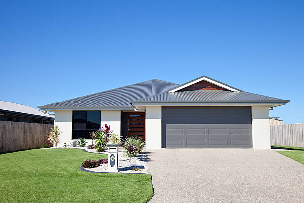 Suburban Family Home "Front of a new neat modern single story family home with landscaped gardens, green grass and blue sky for copy space." blue front door stock pictures, royalty-free photos & images