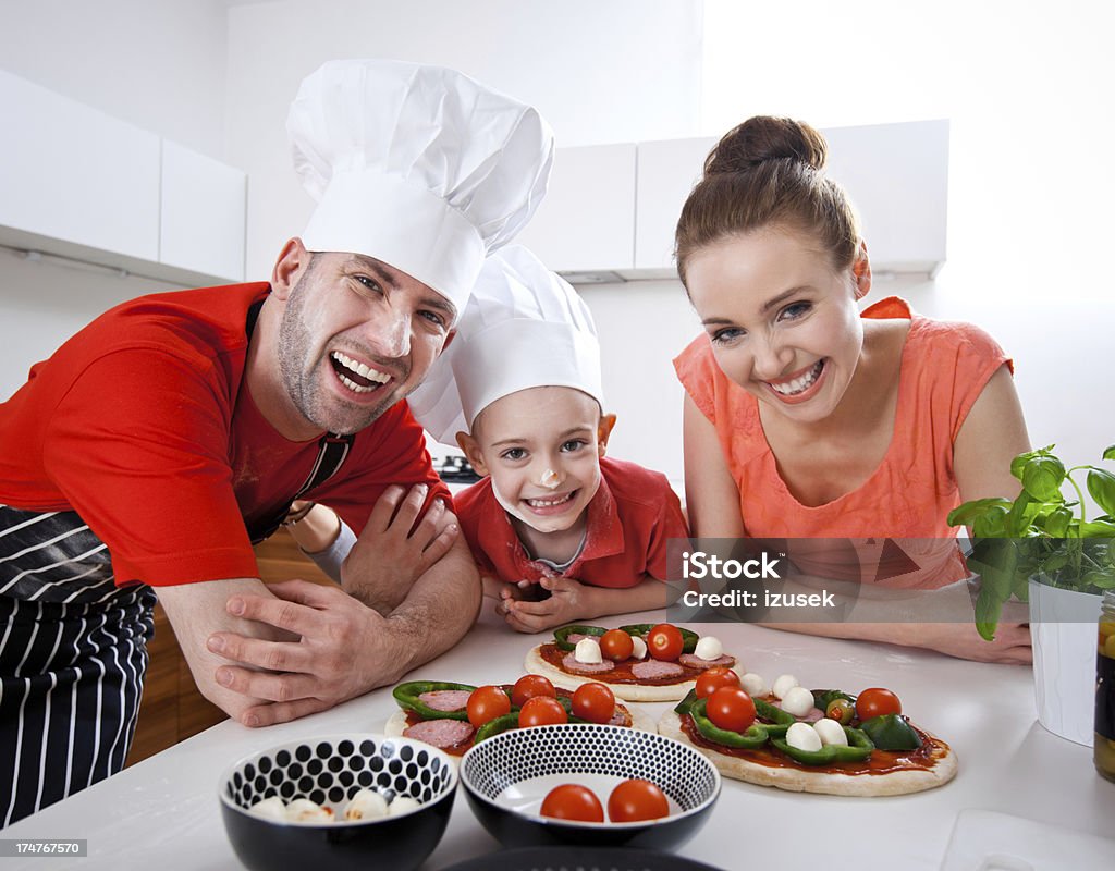 Happy Family Cooking Together "A happy parents with their little son cooking homemade pizza together in the domestic kitchen, laughing at the camera." Close-up Stock Photo