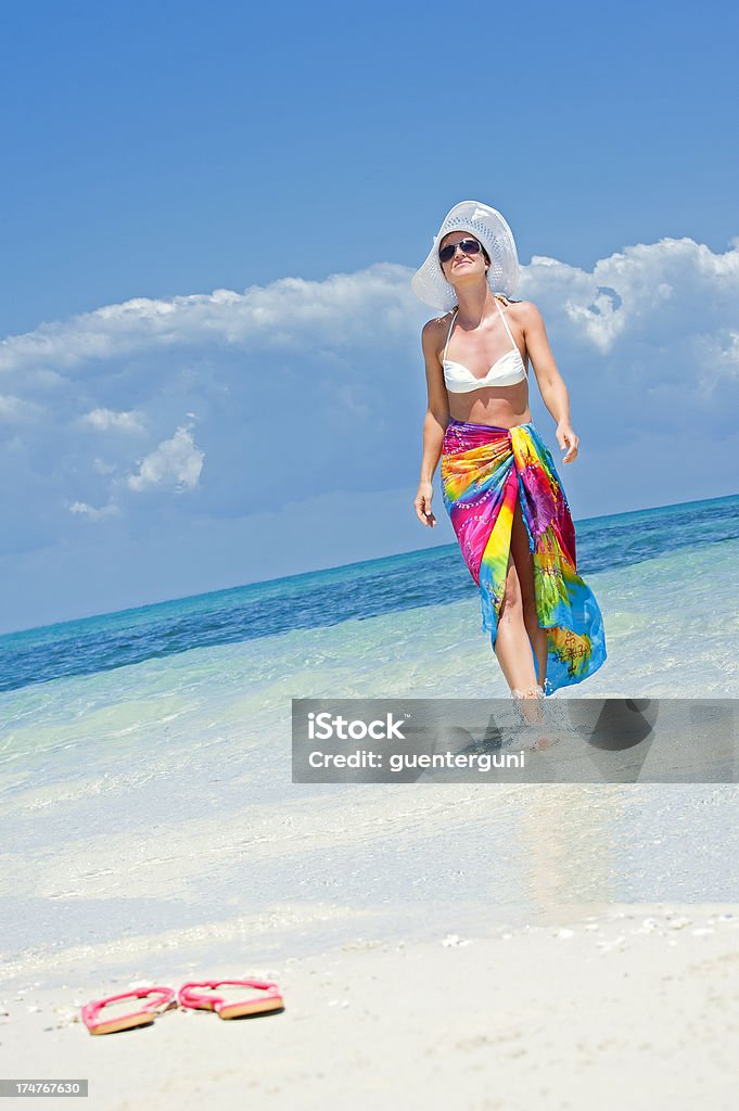 Elegante donna con cappello a piedi sulla spiaggia - Foto stock royalty-free di Acqua