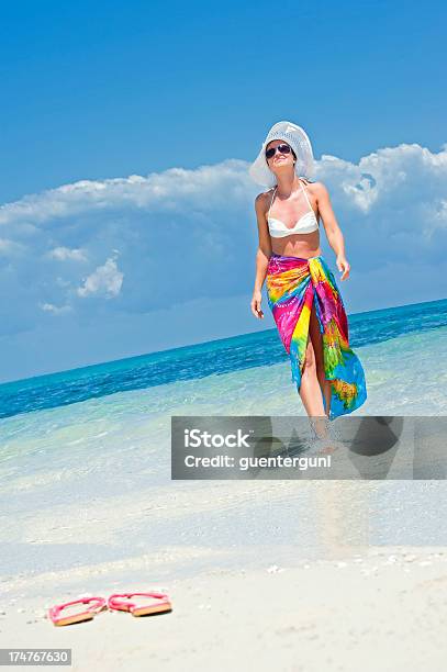 Foto de Elegante Mulher Com Chapéu Caminhando Na Praia e mais fotos de stock de Adulto - Adulto, Atividade Recreativa, Azul Turquesa