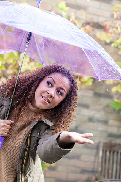 istock Woman checking for rain under umbrella 174767844