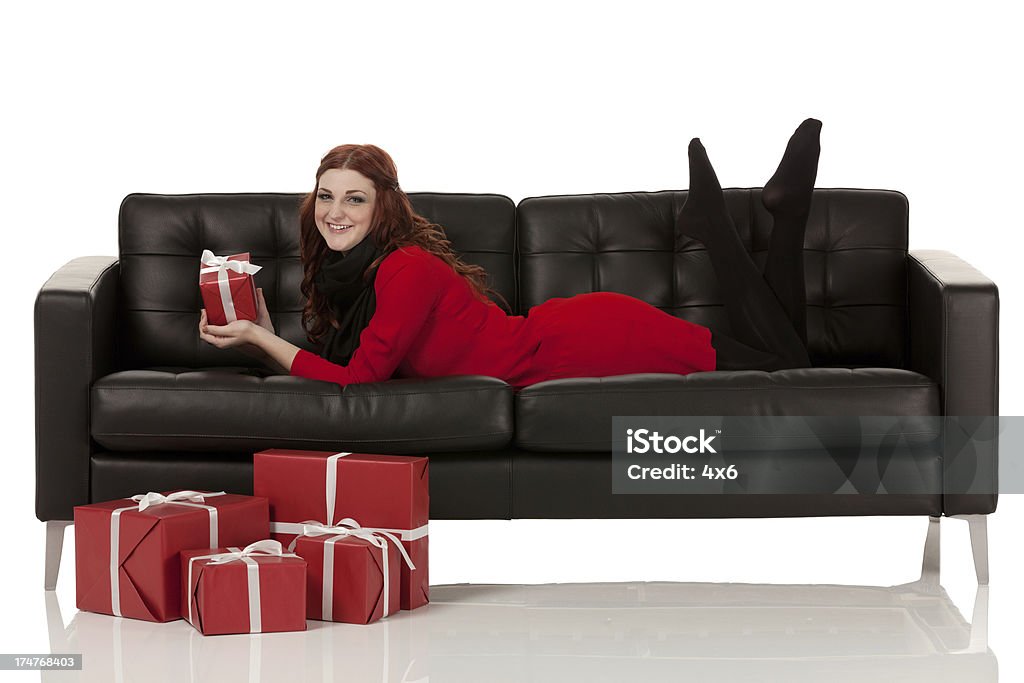 Hermosa mujer estar recostado en un sofá con regalos de Navidad - Foto de stock de 20 a 29 años libre de derechos