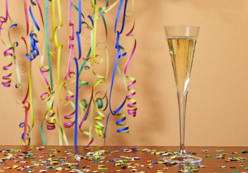Happy New Year with glass of champagne and paper streamer confetti. Bubbles in champagne.