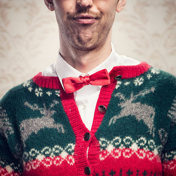 Christmas Sweater Nerd A man in a knit reindeer Christmas cardigan button up sweater, complete with matching red bow tie and a classy mustache.  Damask style vintage wall paper in the background.  Square crop. nerd sweater stock pictures, royalty-free photos & images
