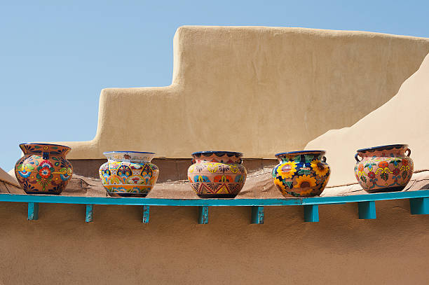 Southwestern Pots on a Ledge "Five empty but colorful pots sit on an old slumping ledge on the roof of an adobe pueblo building in Taos, New Mexico.  There is plenty of copy space available." adobe material photos stock pictures, royalty-free photos & images