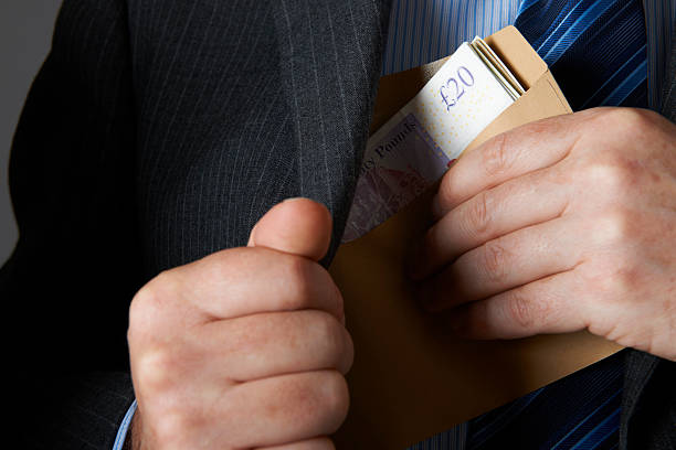 Businessman Putting Envelope Of Sterling Notes In Jacket Pocket Corporate greed and corruption bribing stock pictures, royalty-free photos & images