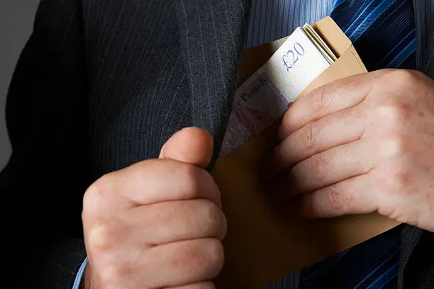 Photo of Businessman Putting Envelope Of Sterling Notes In Jacket Pocket