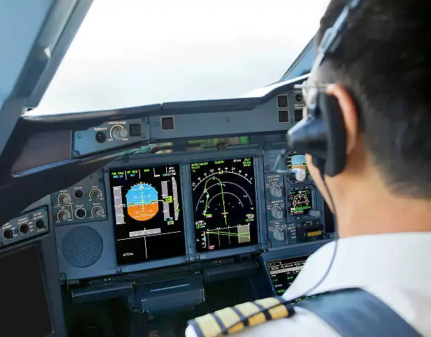 An airline pilot at the controls in an Airbus A380 Flight Deck.