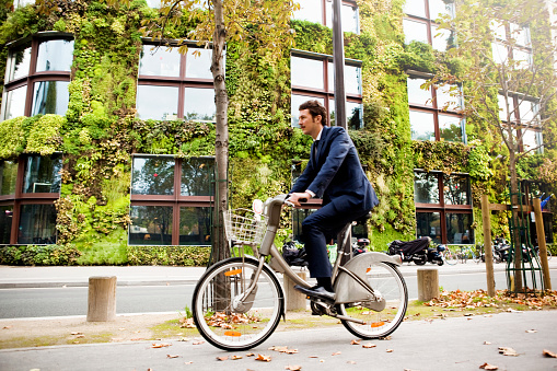 Man riding bike in front of a building covered with a vertical garden