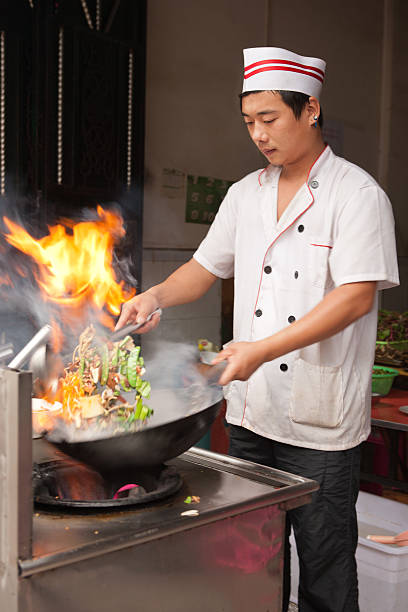 Chinese chef Chinese chef cooking with a wok in his kitchen japanese chef stock pictures, royalty-free photos & images