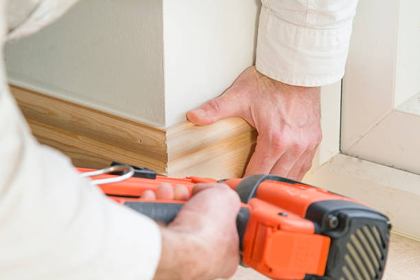 Carpenter fitting base board or skirting with a nail gun stock photo