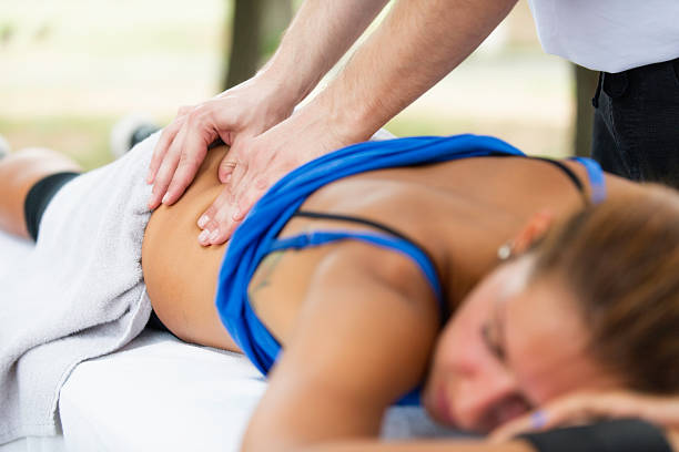 スポーツマッサージ - massaging massage therapist rear view human hand ストックフォトと画像