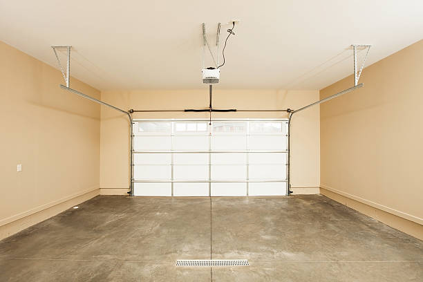 Two Car Garage Interior with Door "An interior view of a new two car garage with garage door, opener and a floor drain. The walls have been insulated, sheetrocked and painted." garage door opener photos stock pictures, royalty-free photos & images