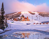 Sheregesh ski resort in Russia, picturesque sunrise, pink cloud on sky, white snow slopes and trails, view on mountain Green (mount Zelenaya), hotels, lift stations, Russia, Siberia. Panoramic