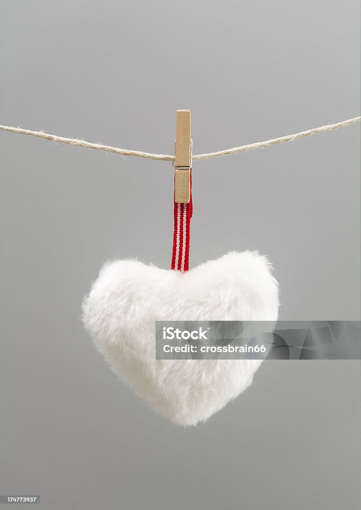 Fluffy white heart hanging from clothesline One fluffy white heart dangling from clothesline with ample copy space. Useful for full page background. Studio macro shot with selective focus on the heart and grey background. Backgrounds Stock Photo