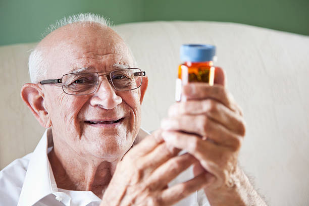 uomo anziano leggendo bottiglie di medicina - sc0570 foto e immagini stock