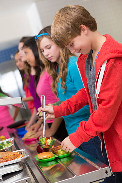 feliz medio school students llegar sus alimentos en cafeteria línea - tray lunch education food fotografías e imágenes de stock