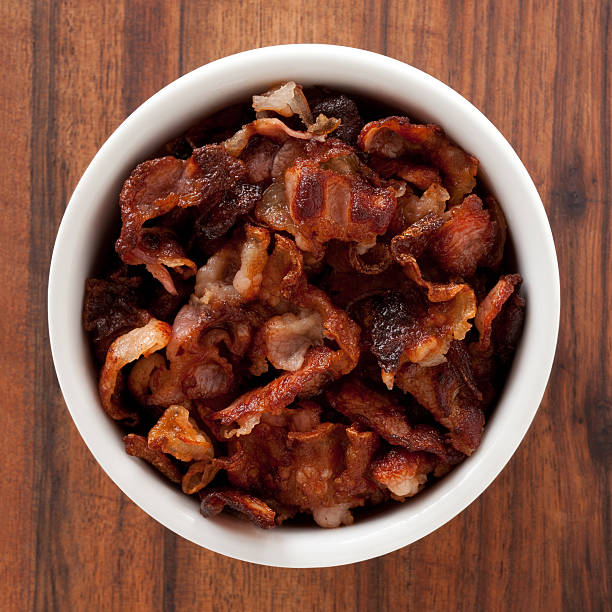 Fried bacon Top view of white bowl full of fried bacon cooked bacon slice stock pictures, royalty-free photos & images