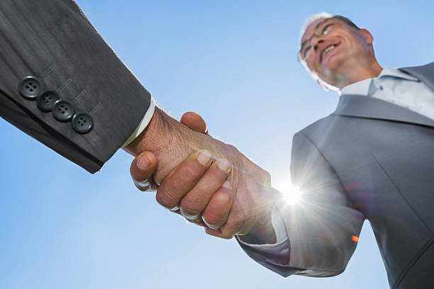 istock Businesspeople shaking hands against the sky. 174774586