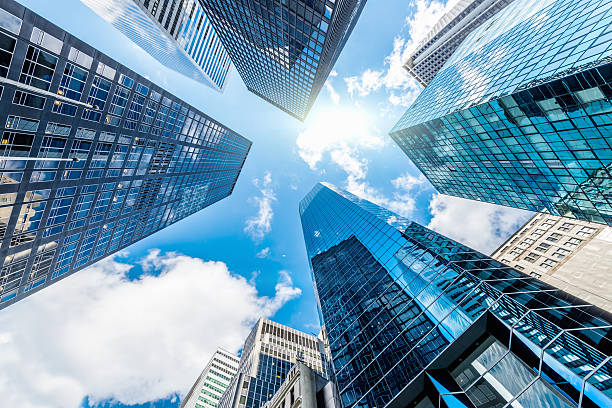 Blue Manhattan Skyscapers Wall Street New York City Reflecting Blue Skyscraper Buildings at Wall Street financial district in New York City from below against the sun. below stock pictures, royalty-free photos & images