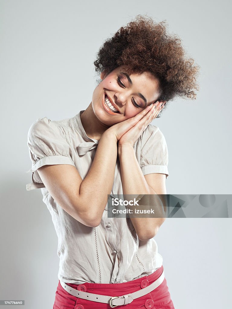 Relaxation Portrait of cute teenaged afro girl standing with eyes closed against grey background. Studio shot. Portrait Stock Photo