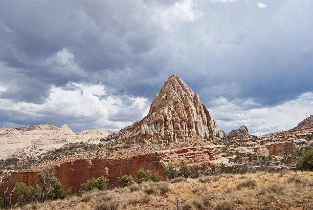 Storm Clouds Over Pectol's Pyramid Pectols Pyramid (6940') was named for Ephraim Portman Pectol who was instrumental in the early efforts to establish protection for the area. Pectols Pyramid is a sandstone monolith near the main road through the park. It is best seen from the Hickman Bridge Trail where it really takes on its pyramid shape. Pectols Pyramid is in Capitol Reef National Park near Fruita, Utah, USA. jeff goulden capitol reef national park stock pictures, royalty-free photos & images
