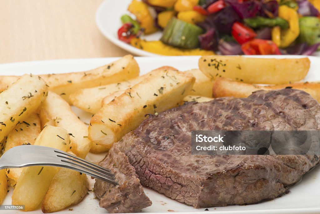 Rump steak and fries dinner Rump steak and chunky herby fries dinner with a side dish of roasted mixed vegetables - studio shot Barbecue - Meal Stock Photo