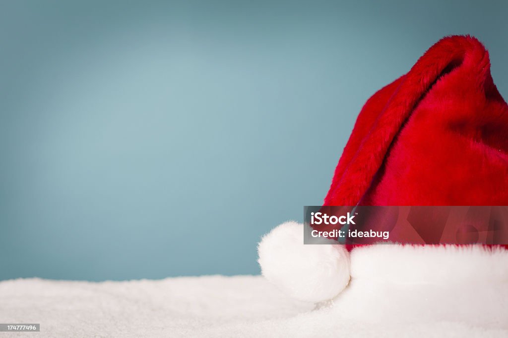 Santa Hat siedzi w śniegu z kopii przestrzeni - Zbiór zdjęć royalty-free (Barwne tło)