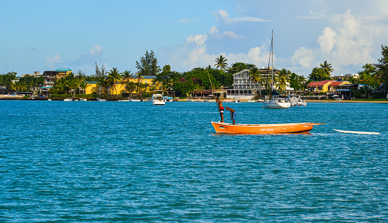 Grand Baie, Mauritius - Jan 9, 2017. Local men rowing boat on sea in Grand Baie, Mauritius. Mauritius, an Indian Ocean island nation, is known for its beaches, lagoons and reefs.