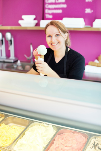 Smiling ice cream store employee holding a delicious cone