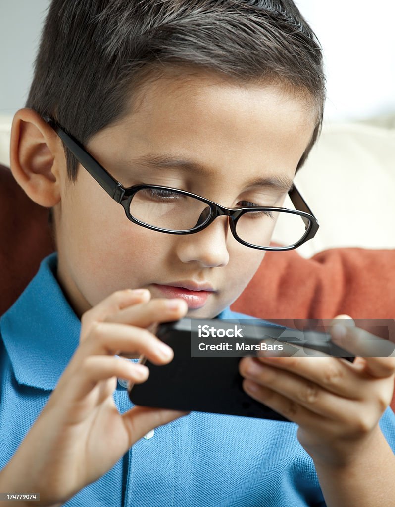 Ребенок с очки играет на смартфоне - Стоковые фото 6-7 лет роялти-фри