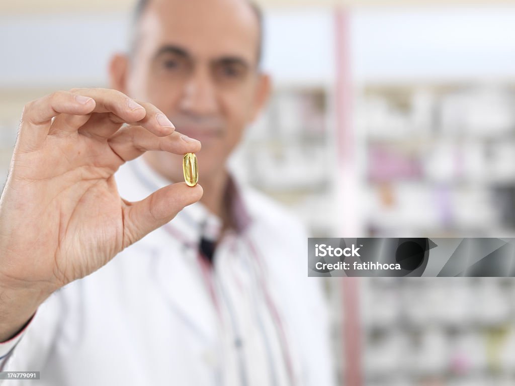 Yellow Pill Pharmacist is holding yellow pill. Passing - Giving Stock Photo