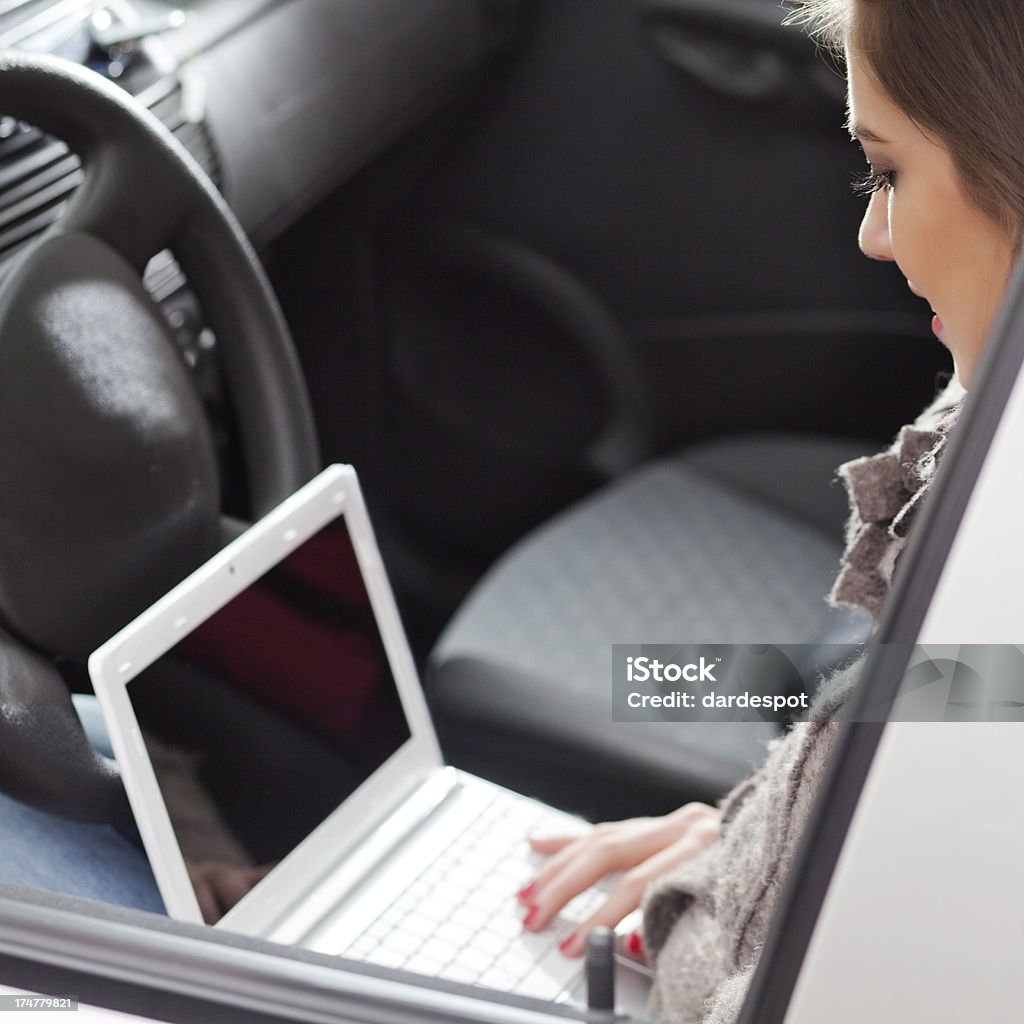 Junge Frau Tippen auf Notebook in einem Auto - Lizenzfrei Arbeiten Stock-Foto