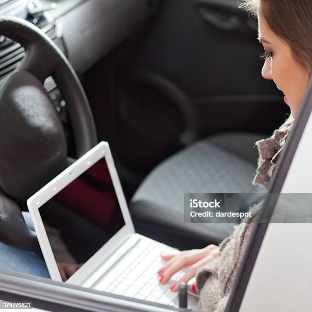 Junge Frau Tippen Auf Notebook In Einem Auto Stockfoto und mehr Bilder von Arbeiten - Arbeiten, Attraktive Frau, Auto