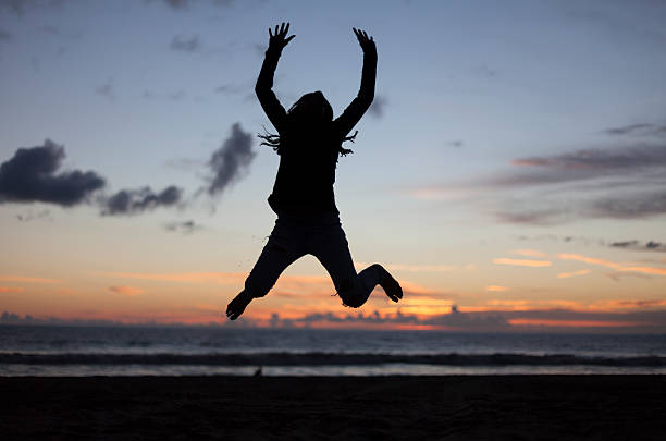 силуэт девушки, прыжки на пляже на закате - arms outstretched teenage girls jumping flying стоковые фото и изображения