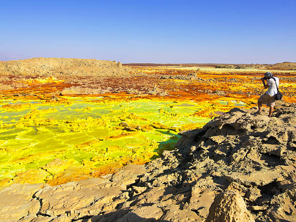 Dallol Photo "Tourist is taking photo at Dallol volcano, which is known for activity and areas like Hot Springs with beautiful colors from different minerals. Living conditions are the worsteds on earth and this is a place where the army and police protection is needed. Near is Hamed a is small town and it is in Afar country in Danakil Depression, North east Ethiopia." dallol ethiopia stock pictures, royalty-free photos & images