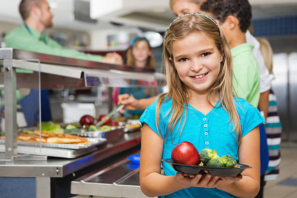 école élémentaire étudiants faisant des choix équilibrés dans la cafétéria ligne - red delicious apple apple fruit vertical photos et images de collection