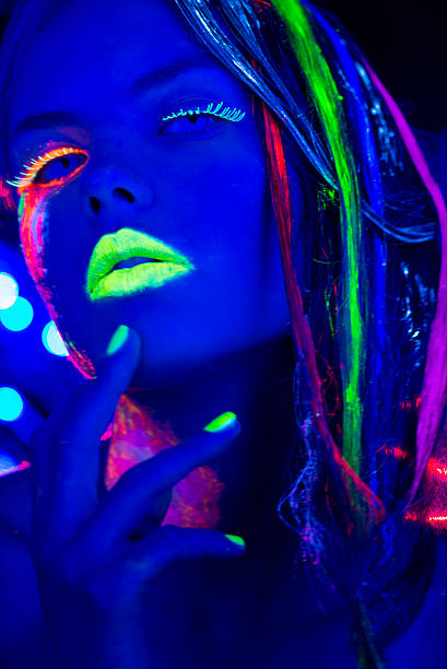 istock Women Portrait with Glowing Multi Colored makeup on black light 174781952
