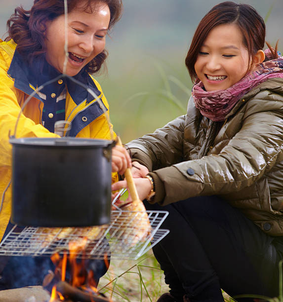 istock happy mother and daughter roasting fish outdoor 174782143