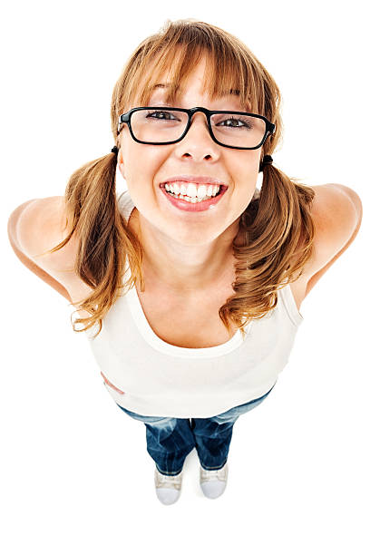 Closeup high-angle wide shot of a teenage girl nerd wearing black rimmed glasses and a bright happy smile.