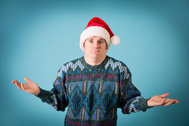 man with irritated look wearing santa hat and ugly sweater - santa hat bildbanksfoton och bilder