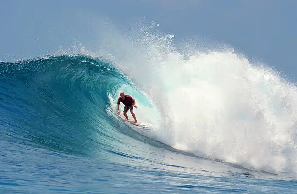 Surfer rides a large blue tropical wave