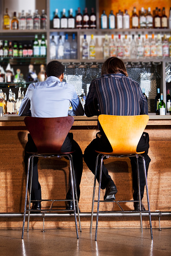 Rear view of multi-ethnic men having drinks at bar.