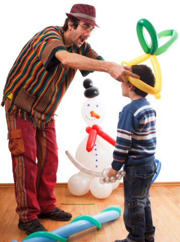 Entertainer at birthday party making balloon animals and objects for a little boy.